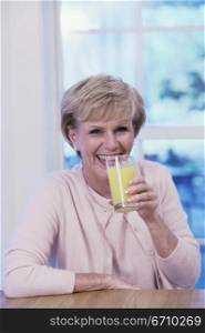 Portrait of an elderly woman drinking a glass of orange juice