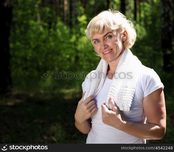 Portrait of an elderly woman in sportswear with a towel. The symbol of healthy lifestyles.