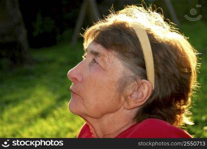 Portrait of an elderly woman outside with backlit hair