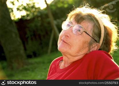 Portrait of an elderly woman outside with backlit hair