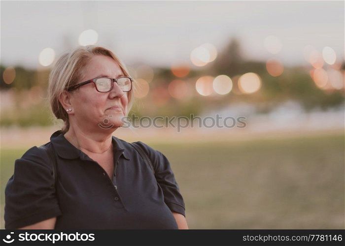 Portrait of an elderly woman with blonde hair and glasses on the beaches of the Mediterranean Sea at sunset. Selective focus. High-quality photo. Portrait of an elderly woman with blonde hair and glasses on the beaches of the Mediterranean Sea at sunset. Selective focus 