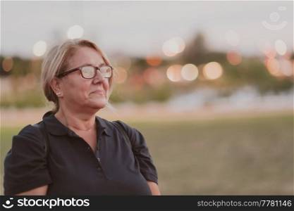 Portrait of an elderly woman with blonde hair and glasses on the beaches of the Mediterranean Sea at sunset. Selective focus. High-quality photo. Portrait of an elderly woman with blonde hair and glasses on the beaches of the Mediterranean Sea at sunset. Selective focus 