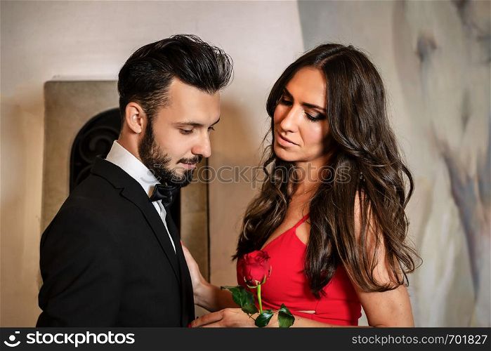 Portrait of an elegant couple on a romantic date - the gentleman giving a red rose to the lady