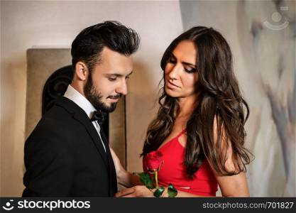 Portrait of an elegant couple on a romantic date - the gentleman giving a red rose to the lady