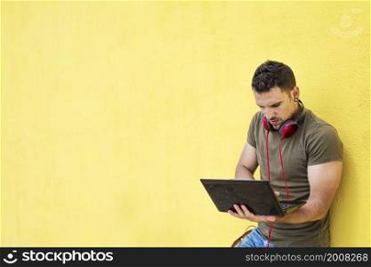 Portrait of an excited man holding laptop computer isolated on yellow background, Feeling happiness, Hispanic Male model