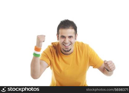 Portrait of an excited young man cheering with clenched fists over white background