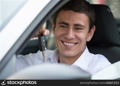 Portrait of an happy handsome guy with keys in his new car