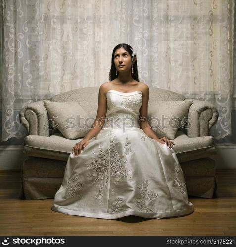 Portrait of an Indian bride sitting on a love seat.