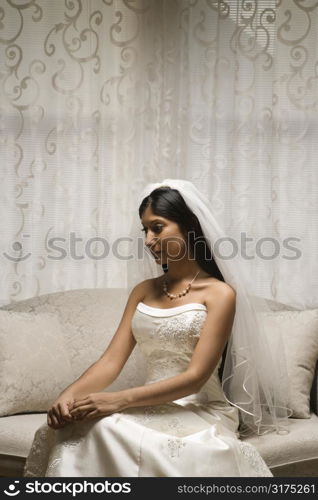 Portrait of an Indian bride sitting on a love seat.