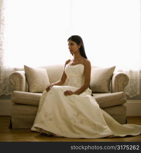 Portrait of an Indian bride sitting on a love seat.