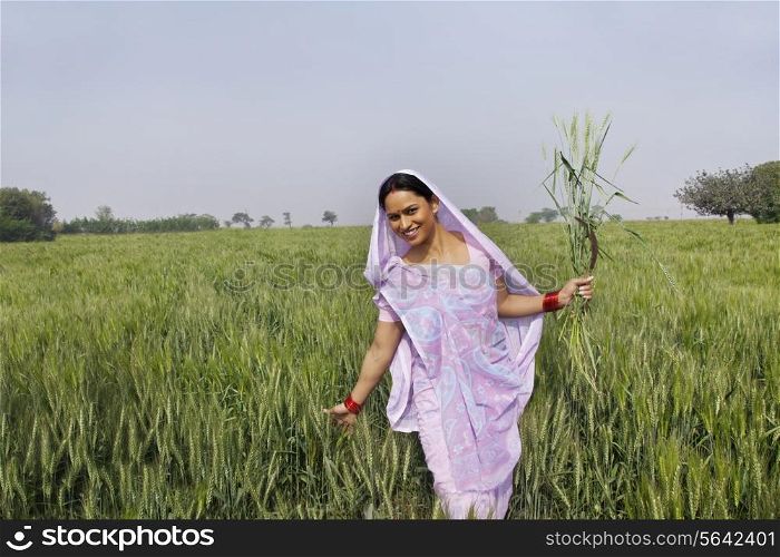 Portrait of an Indian female farm worker gliding through wheat field