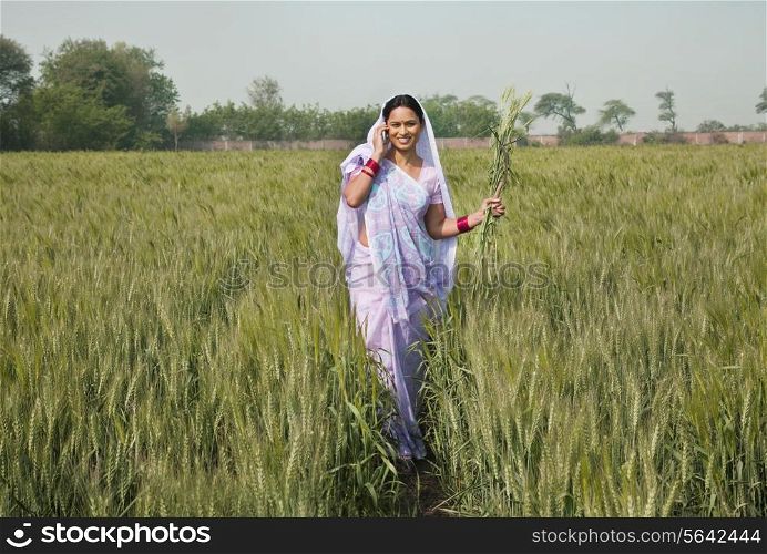 Portrait of an Indian female worker talking on phone while walking in the field