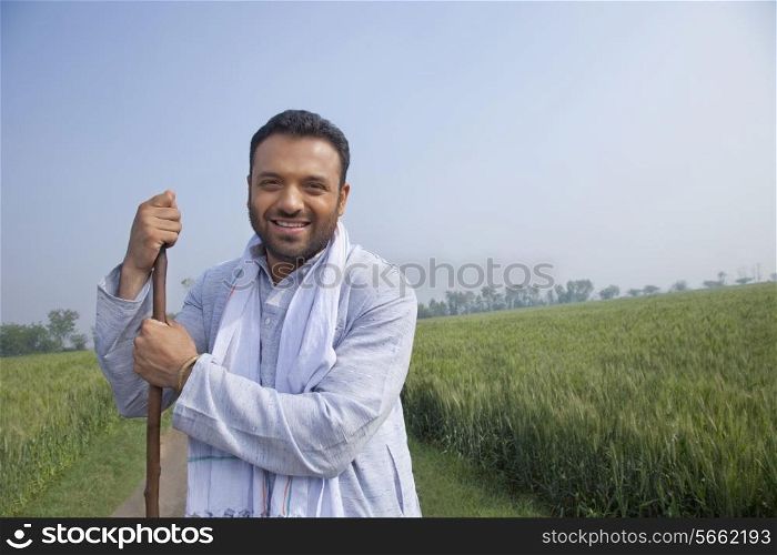 Portrait of an Indian man looking away while holding a stick