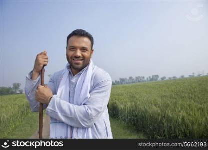 Portrait of an Indian man looking away while holding a stick