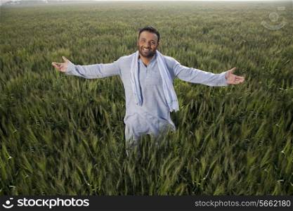 Portrait of an Indian man standing with arms out in a field