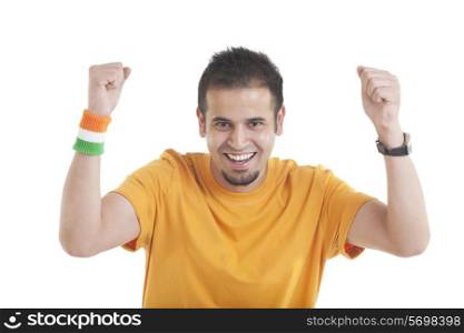 Portrait of an Indian young man with tricolor wristband in hand cheering up over white background
