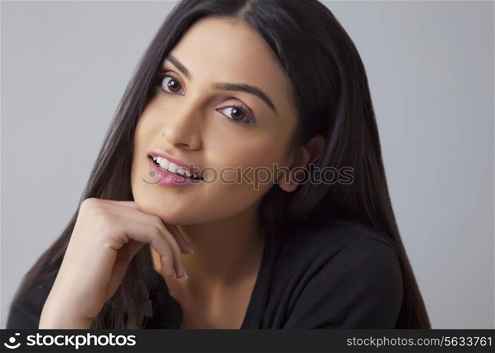 Portrait of an Indian young woman smiling with hand on chin over colored background