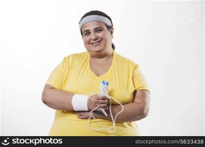 Portrait of an obese female with skipping rope over white background