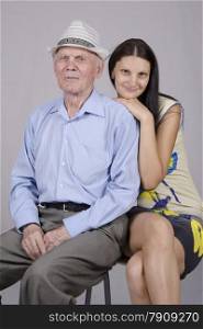 Portrait of an old man eighty years old, on his shoulder was leaning granddaughter twenty years