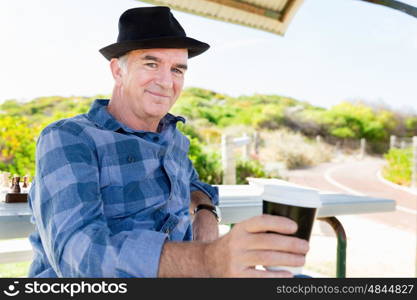 Portrait of an old man outdoors. Nice morning in the park with coffee