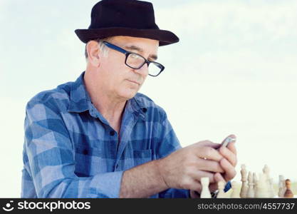 Portrait of an old man with his mobile phone outdoors. Old man with his mobile