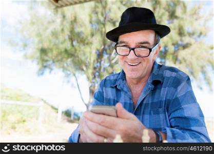 Portrait of an old man with his mobile phone outdoors. Old man with his mobile