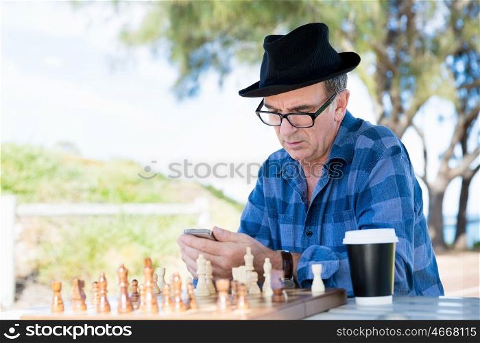 Portrait of an old man with his mobile phone outdoors. Old man with his mobile