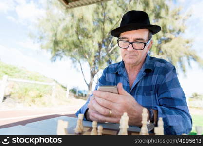 Portrait of an old man with his mobile phone outdoors. Old man with his mobile