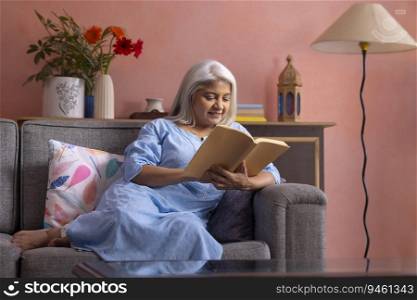Portrait of an old woman reading a book in living room