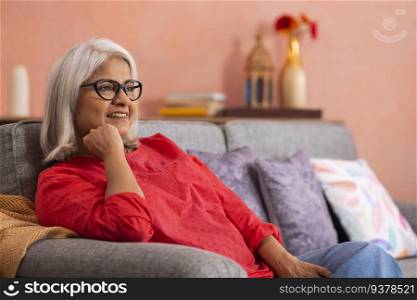 Portrait of an old woman relaxing on sofa in living room