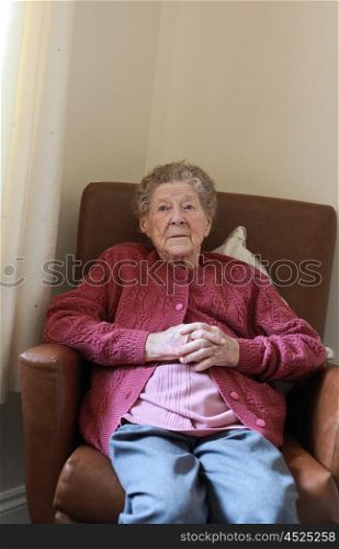 Portrait of an older lady sitting in an armchair in a care home watching television out of frame