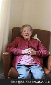 Portrait of an older lady sitting in an armchair in a care home watching television out of frame