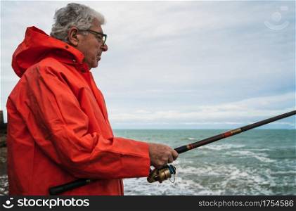 Portrait of an senior man fishing in the sea, enjoying life. Fishing and sport concept.