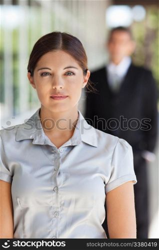 Portrait of an young attractive businesswoman with man standing in background