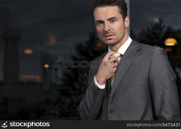 Portrait of angry businessman adjusting necktie in office