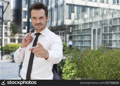 Portrait of angry businessman pointing at you outside office building