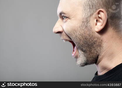 portrait of angry man sreaming isolated on gray background with copyspace