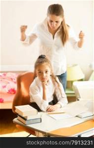 Portrait of angry mother swears on daughter doing homework