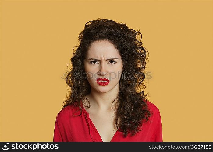 Portrait of angry young woman frowning over colored background