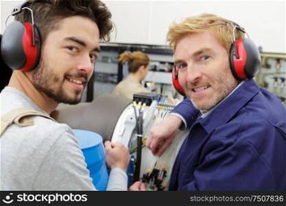 portrait of apprentice electronics technician with supervisor
