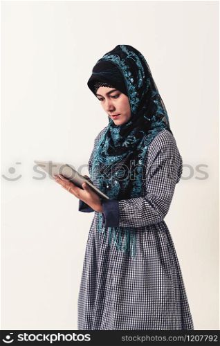 Portrait of Arabic muslim woman in colorful traditional clothes using laptop computer on white background.. Portrait of Arabic woman in traditional clothes.