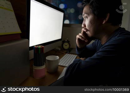 Portrait of Asia Businessman sitting and working hard on the table with front of computer desktop in work place at late with serious action, Work hard and too late concept