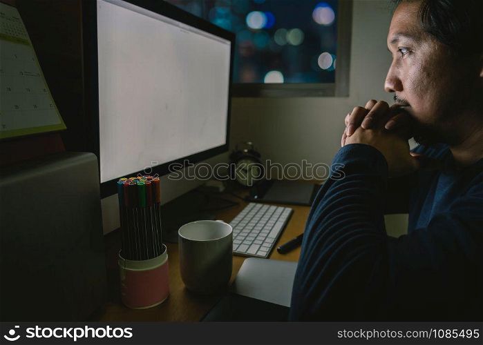 Portrait of Asia Businessman sitting and working hard on the table with front of computer desktop in work place at late with serious action, Work hard and too late concept