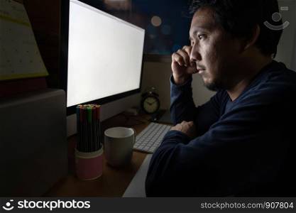 Portrait of Asia Businessman sitting and working hard on the table with front of computer desktop in work place at late with serious action, Work hard and too late concept