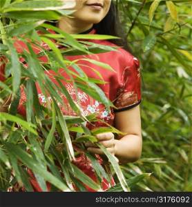 Portrait of Asian American woman in ethnic attire in bamboo forest in Maui, Hawaii.