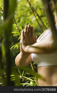 Portrait of Asian American woman in fitness attire standing in yoga position in bamboo forest in Maui, Hawaii.