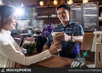 Portrait of asian barista hold take away coffee cup and serving to customer in cafe.