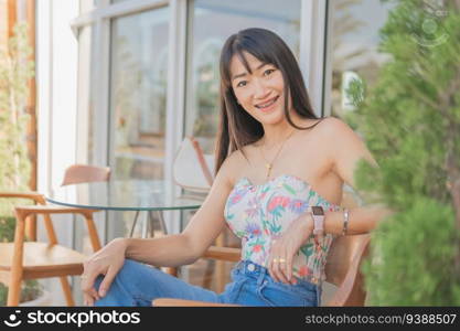 Portrait of asian beautiful sexy asian woman sitting smiling and relaxing Wearing a white strap≤ss dress and jean skirt in a coffee shop