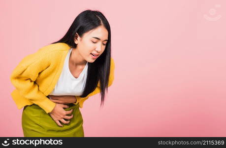 Portrait of Asian beautiful young woman has stomachache, female abdominal pain suffering from stomach ache, studio shot isolated on pink background, Health and medical gastritis concept