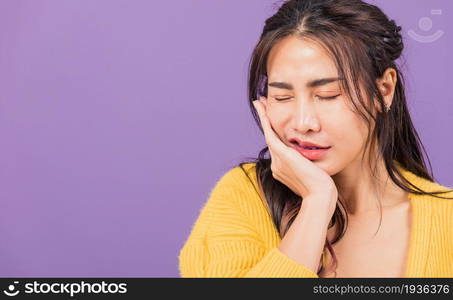 Portrait of Asian beautiful young woman suffering from toothache, female terrible strong teeth pain problem pressing hand to chin, studio shot isolated on purple background, Dental health care concept